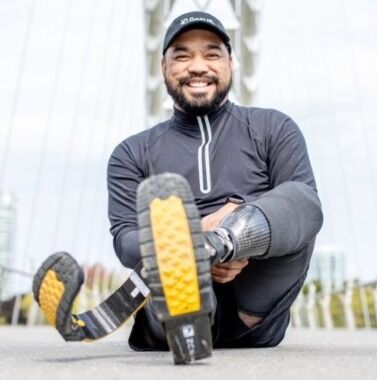 Aristotle Domingo is smiling. Posed sitting with his two running blades on. Aristotle Domingo is smiling. Posed sitting with his two running blades on.